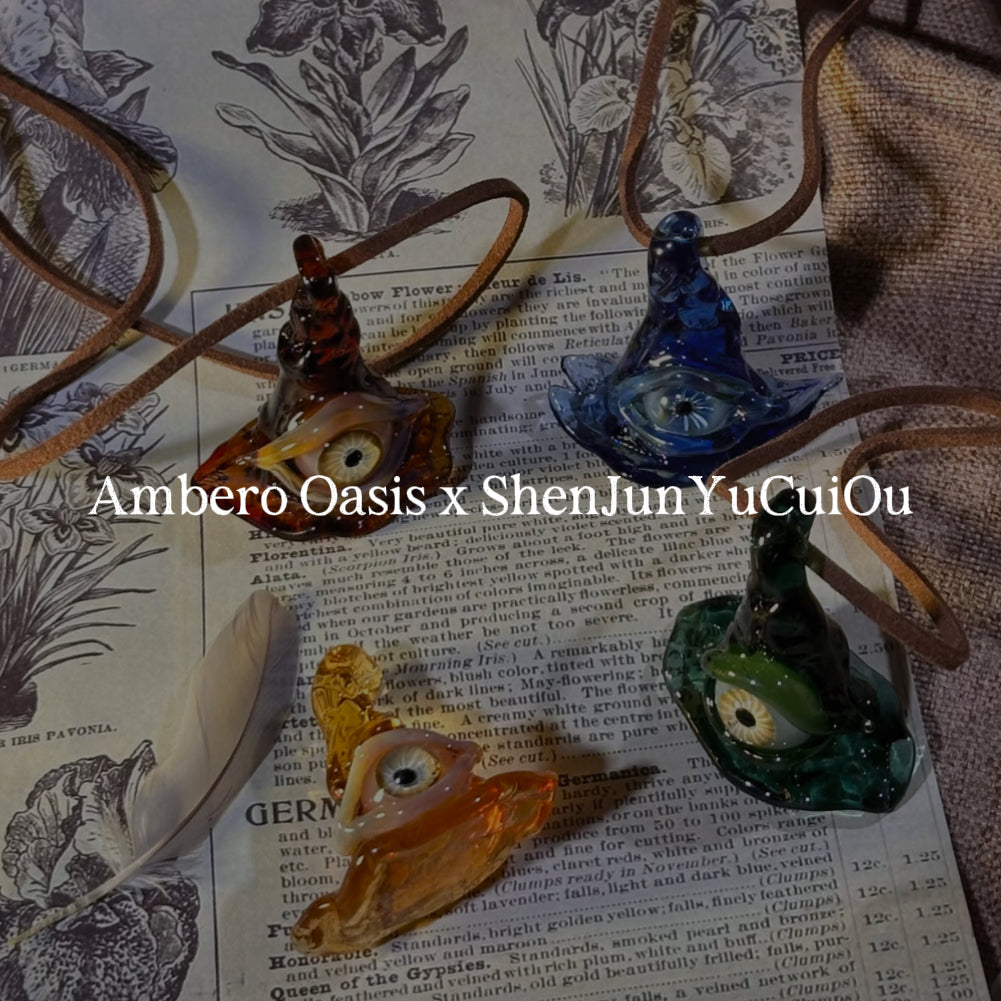 Magical lampwork glass pendants shaped like colorful witch hats resting on an open vintage book.