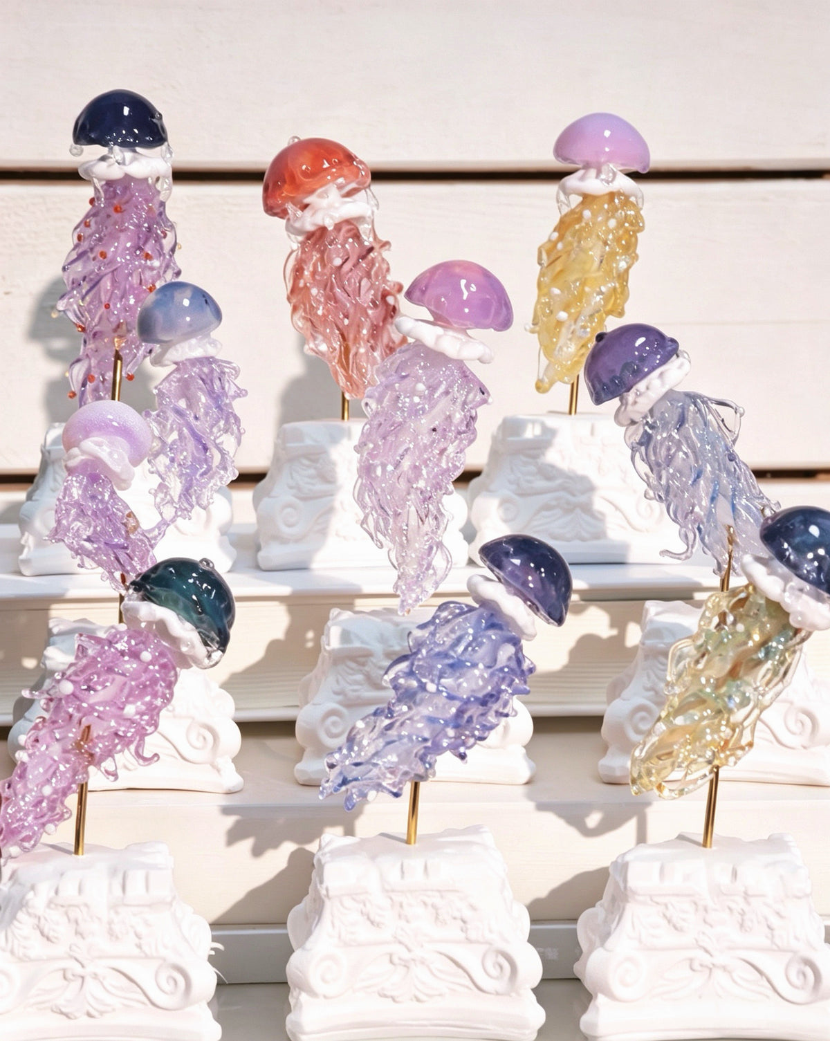 A collection of Hand-Blown Glass Jellyfish Blind Box figurines by Ambero Oasis, showcasing a variety of mesmerizing colors.
