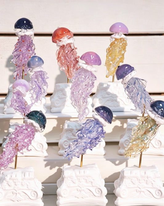 A collection of Hand-Blown Glass Jellyfish Blind Box figurines by Ambero Oasis, showcasing a variety of mesmerizing colors.