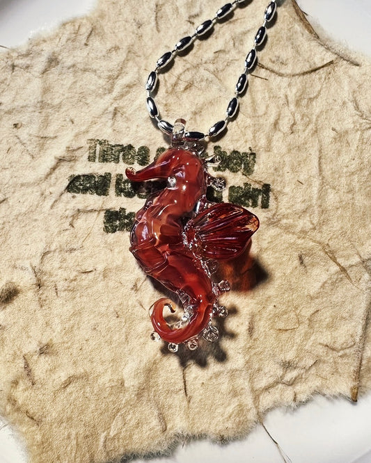 handmade lampwork glass seahorse pendant necklaces on wood background. Includes free titanium steel chain, beaded cord sold separately.