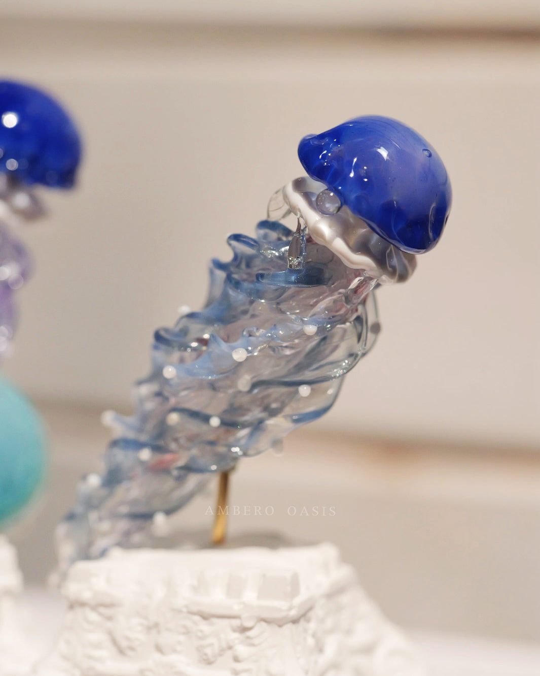 Ocean Blue Series hand-blown glass jellyfish blind box by Ambero Oasis, featuring a vibrant deep blue cap and clear twisted tentacles.