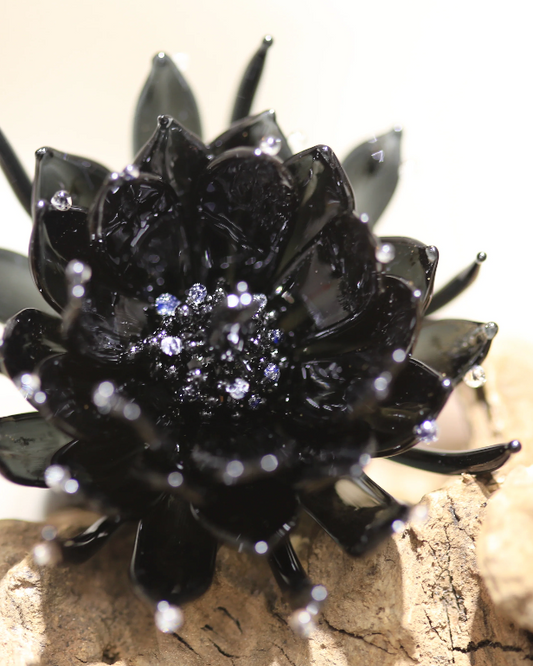Close-up top view of black epiphyllum glass ring showing glossy petals and silver glitter