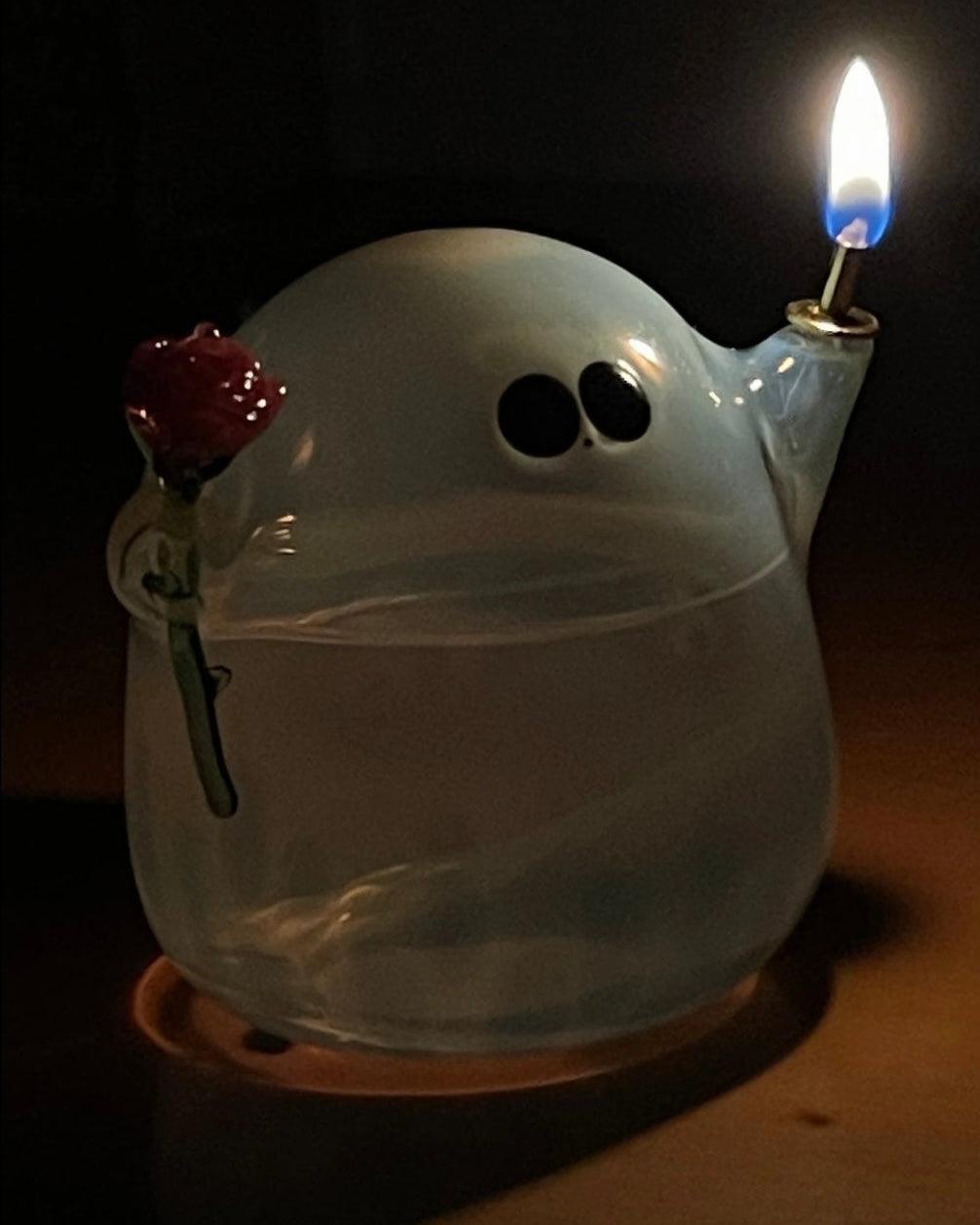 Lighted Halloween ghost butter lamp glowing on wooden table