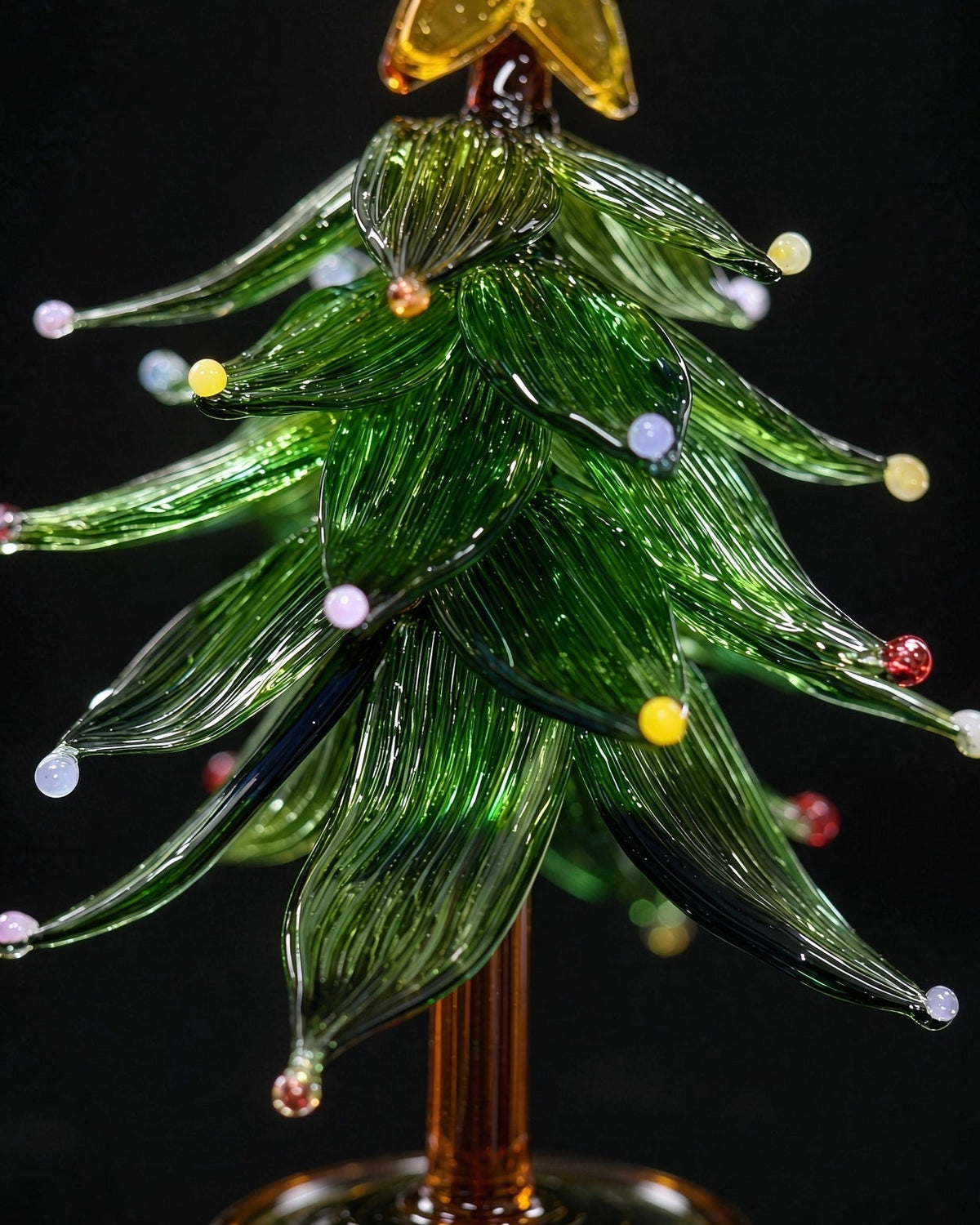 Handmade lampwork glass Christmas tree with star topper and colored dots, miniature tabletop holiday decor with clear base, black background product photography.