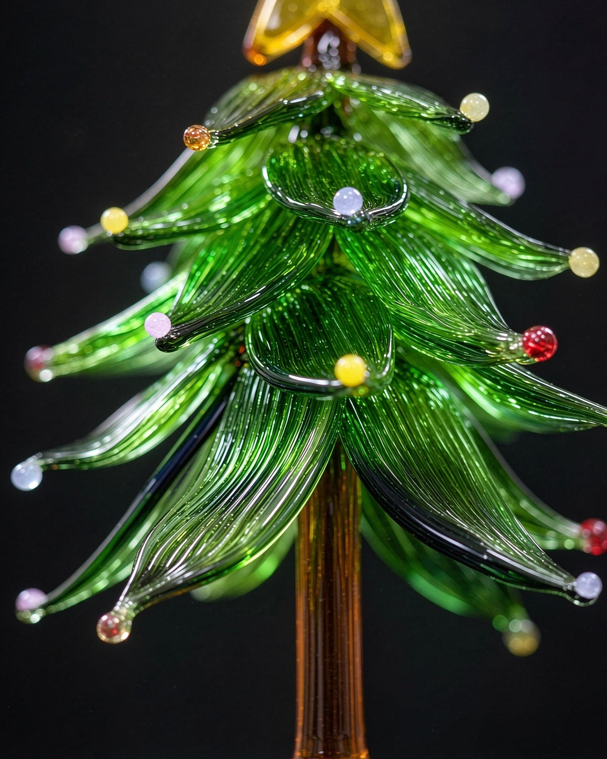 Handmade lampwork glass Christmas tree with star topper and colored dots, miniature tabletop holiday decor with clear base, black background product photography.