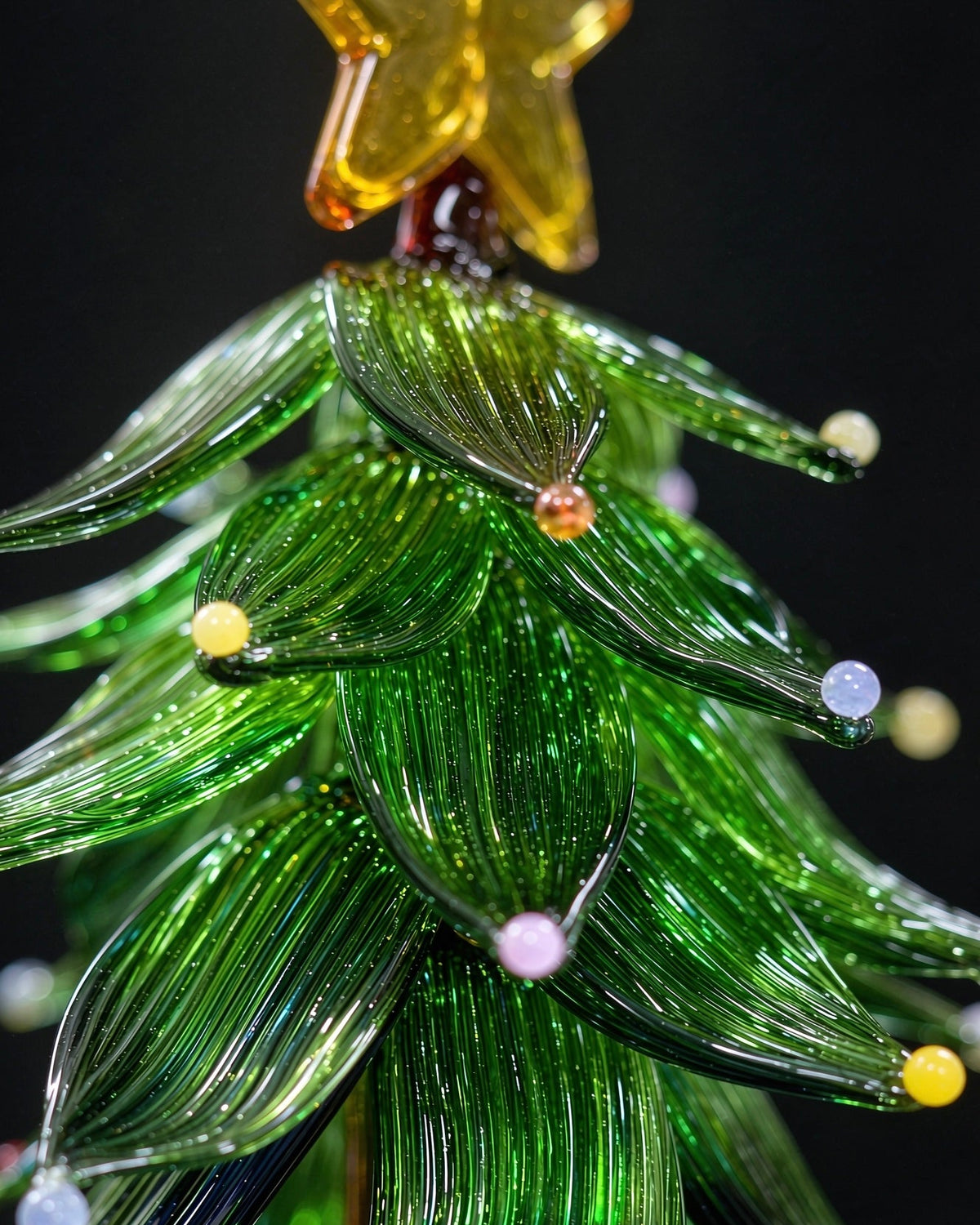 Handmade lampwork glass Christmas tree with star topper and colored dots, miniature tabletop holiday decor with clear base, black background product photography.