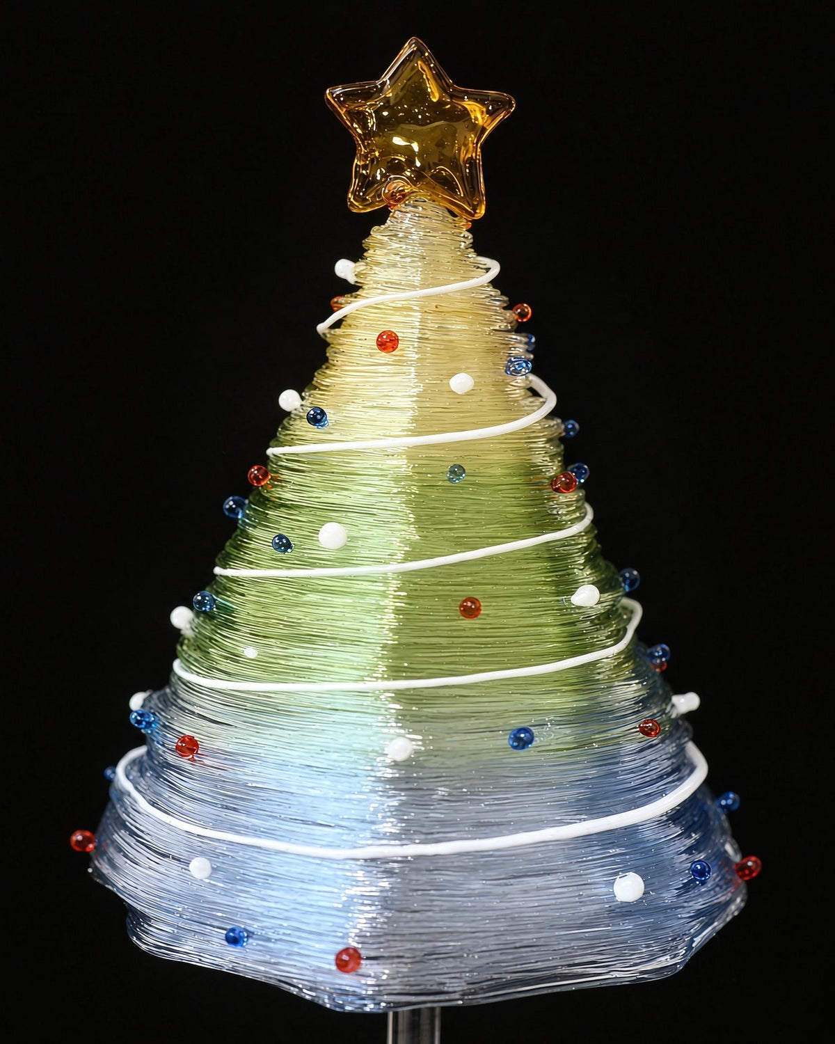 Close-up of gradient green to blue glass Christmas tree with golden star topper