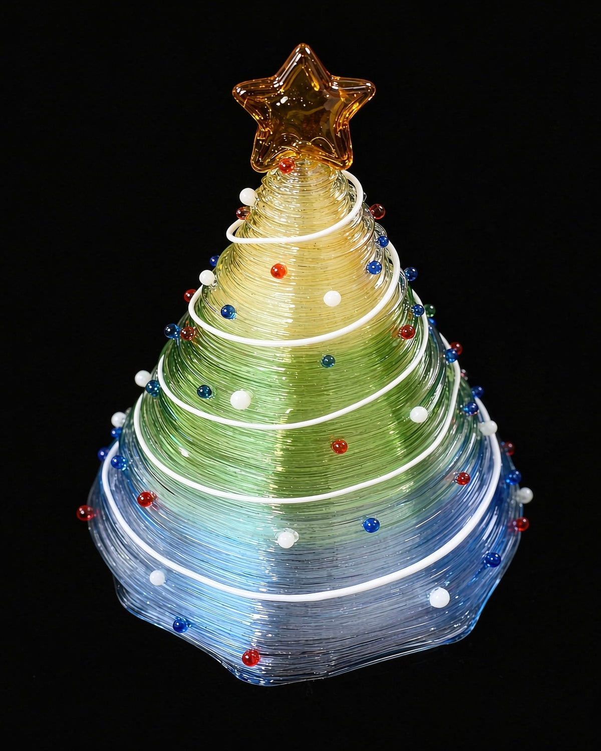 Close-up of gradient green to blue glass Christmas tree with golden star topper